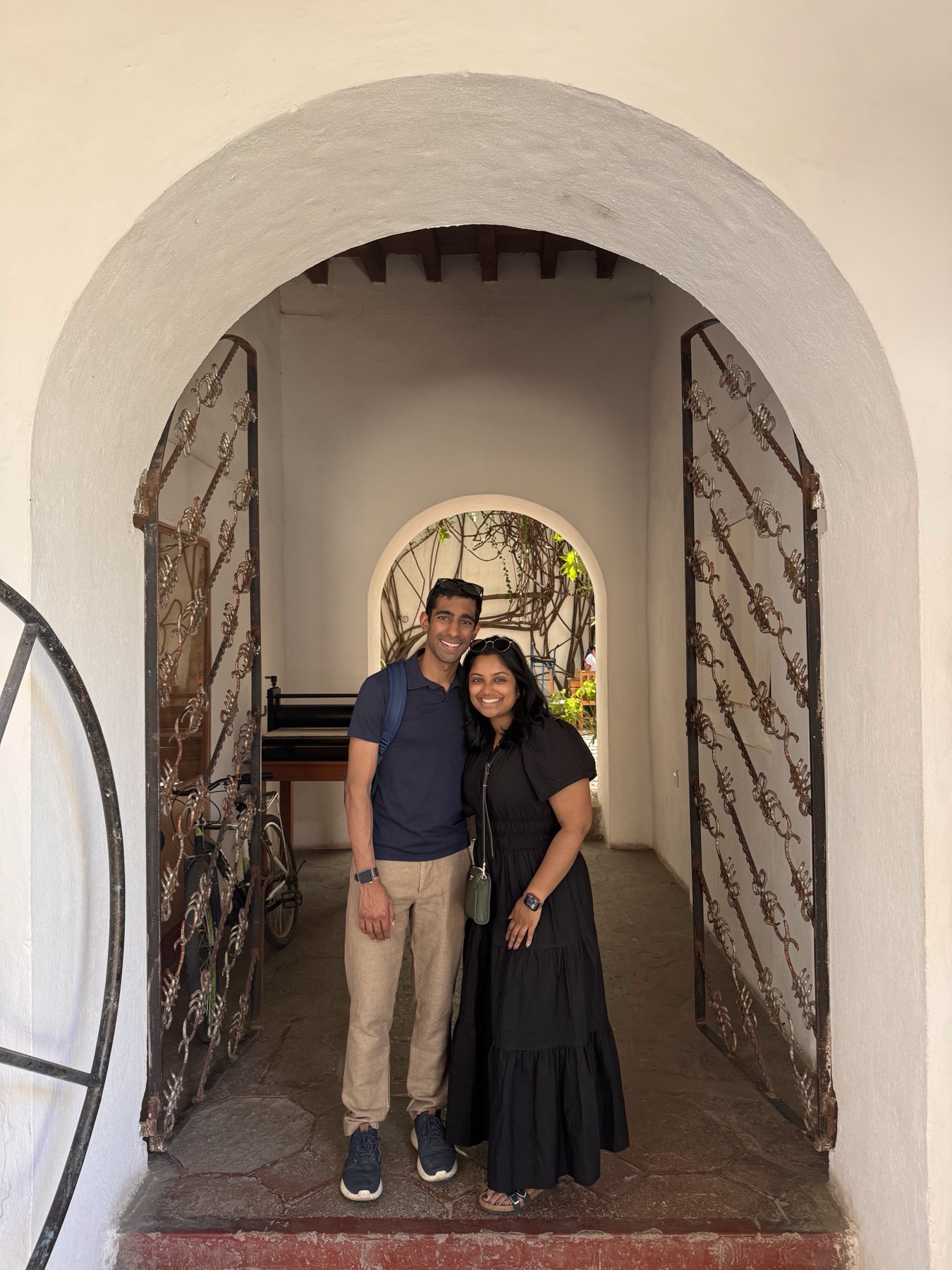 Manu and Nikhil standing in a whitewashed archway in Oaxaca